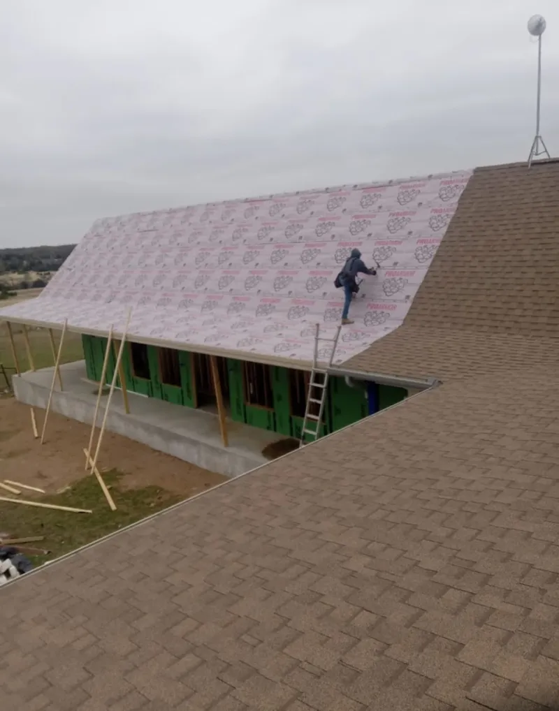 Worker preparing underlayment for a metal roof installation in June Park